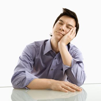 Young Asian business man sitting resting his eyes.