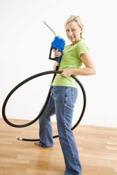 Portrait of adult blonde woman holding gas nozzle like a gun slinger.