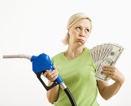 Portrait of distressed adult blonde woman holding gas nozzle and lots of money.