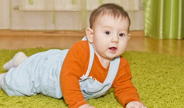 Adorable baby lying on green carpet