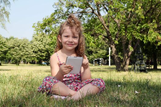 happy little girl with tablet in park