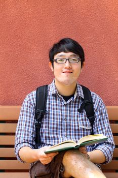 He is reading book on campus.