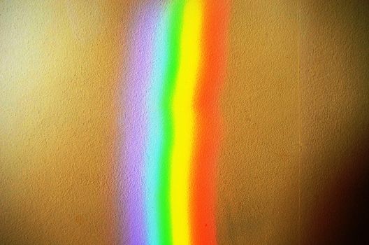 artificial rainbow light closeup on concrete yellow painted wall background.
