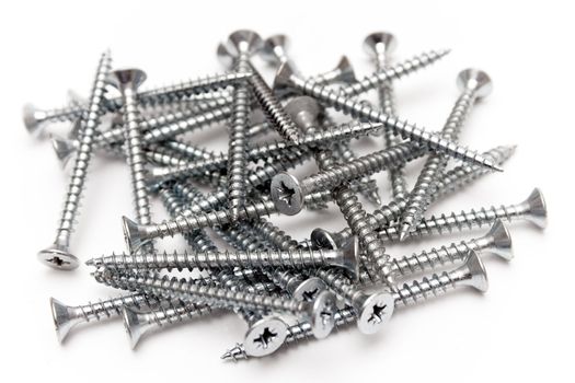 Messy heap of metal screws isolated on a white background.