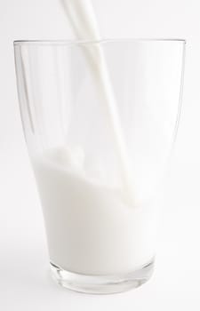 Pouring milk in a glass. White background.
