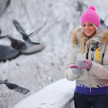 winter women give food to the pigeon