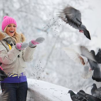 winter women give food to the pigeon