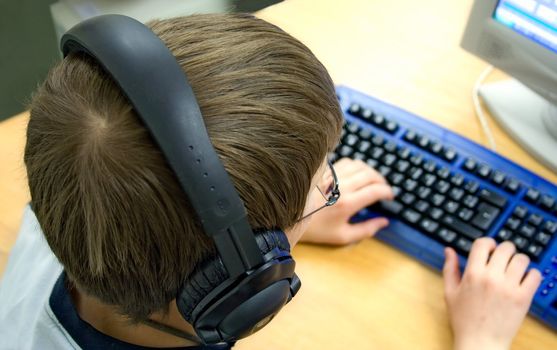 Young boy with headphones using a computer.