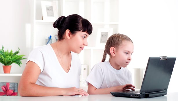 Mom and daughter are working together for a laptop at home