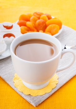 White cup of coffee with breakfast items on the orange textured linen napkin
