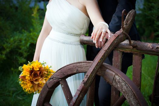 Young married couple holding hands - with wedding bouquet