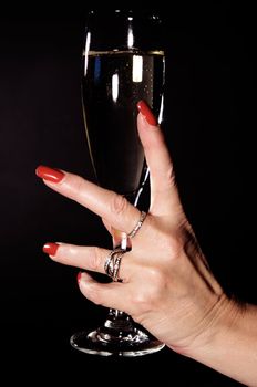 Mature woman holding a glass of champagne. Isolated on a black background.