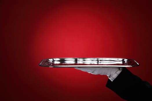 Butler carrying silver serving tray, close-up of hand