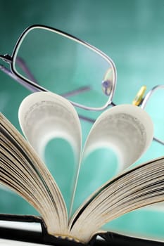 close up of the spectacles on the book with heart shape