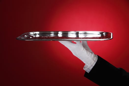 Butler carrying silver serving tray, close-up of hand