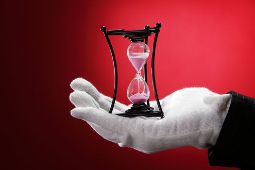 man with the white hand glove holding an hour glass