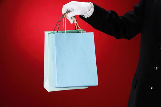 Doorman wearing white gloves, holding shopping bags