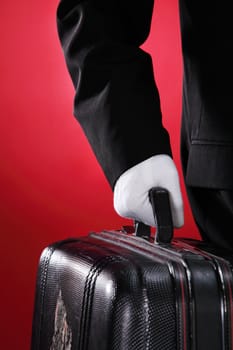 Hotel porter carrying suitcase, close up, side view