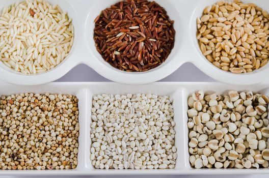  rice , red rice , wheat,  job's tears , barley and millet grains on white bowl