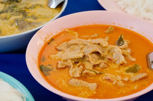 pork in ground peanut-coconut cream curry and different food on blue table