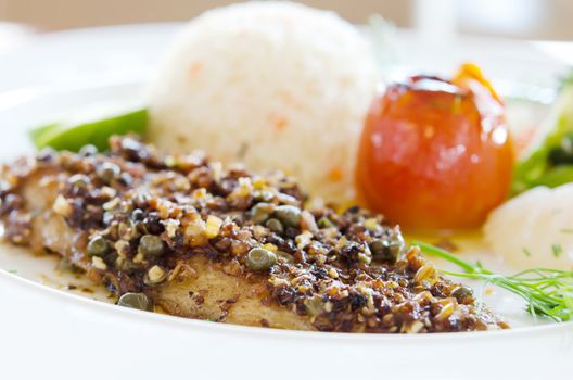 fish steak served with fried rice and vegetable on white dish