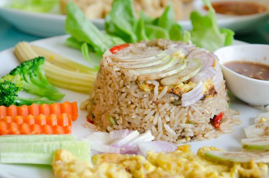mixed cooked rice with shrimp paste sauce , fried egg , fresh vegetable and chili sauce