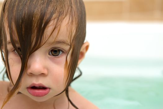 Big eye toddler girl looking glazed with wet hair.