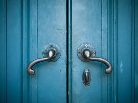 Door handles with an old double door painted with blue