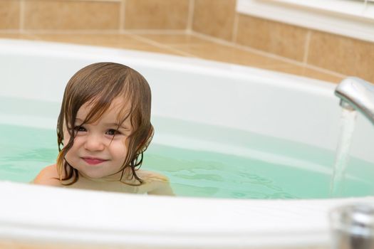 Cute Toddler giving stisfied smile from the bath tub. Copy space on the right.