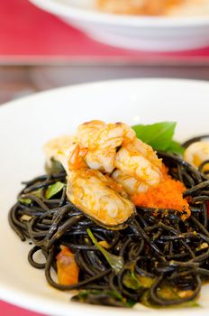 Black spaghetti with green mussel , fish eggs and shrimp  on white plate 