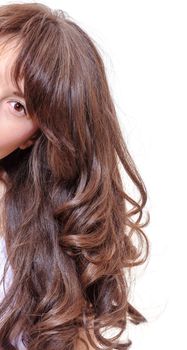 Studio portrait of a seductive young woman with beautiful long wavy brunette hair peering around the edge of the frame with one eye looking at the camera