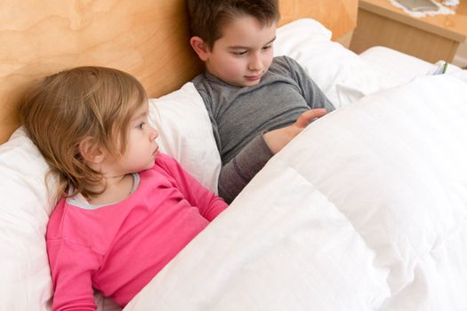 Siblings are reading a book for togetherness.