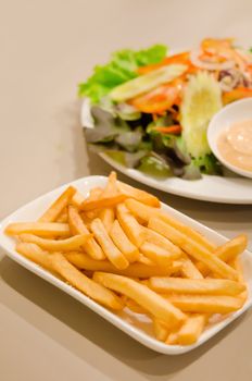  french fries on  white plate served with fresh salad