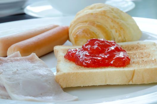 breakfast on white plate (bacon, bread , sausage , toast and jam) 