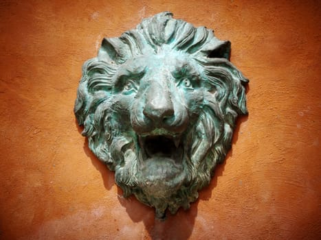 Cast green metal lion head on the orange wall