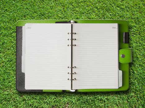 Open Green Cover Binder on Green Grass Background
