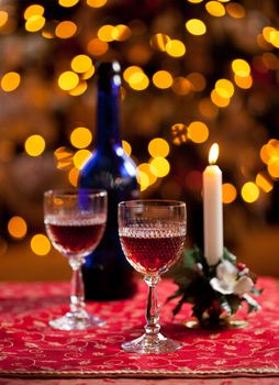 Cut glass sherry or port glasses in front of an out of focus christmas tree with blue bottle