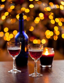 Cut glass sherry or port glasses in front of an out of focus christmas tree with blue bottle