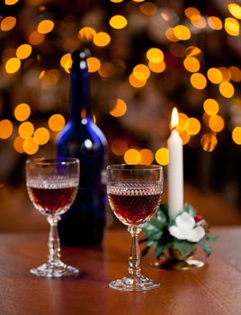 Cut glass sherry or port glasses in front of an out of focus christmas tree with blue bottle