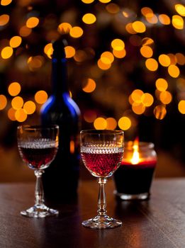 Cut glass sherry or port glasses in front of an out of focus christmas tree with blue bottle