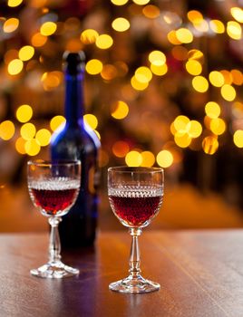 Cut glass sherry or port glasses in front of an out of focus christmas tree with blue bottle