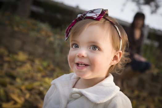 Adorable Baby Girl Playing Outside in the Park with Mom Behind Her.