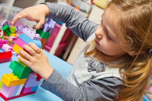 Little girl is playing with building bricks 