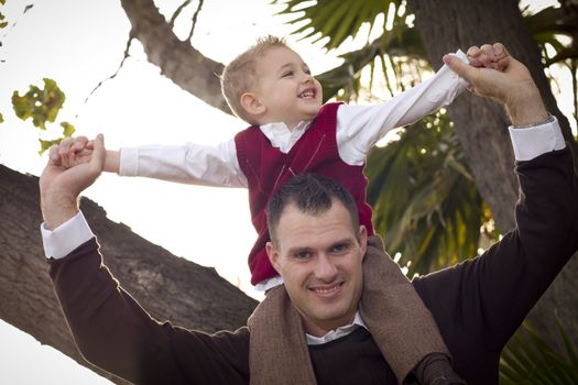 Young Laughing Father and Child Having Piggy Back Fun in the Park.