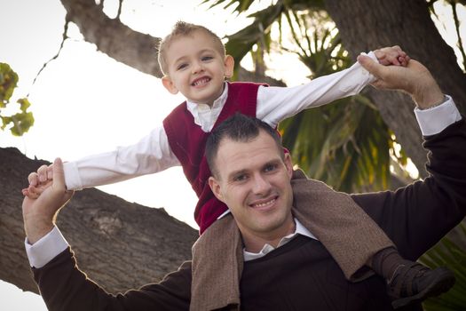 Young Laughing Father and Child Having Piggy Back Fun in the Park.