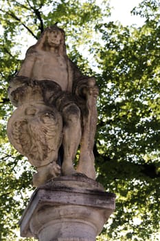 An old statue under trees with local insignia in Krems, Austria