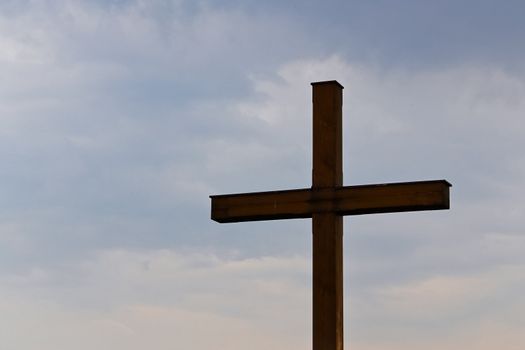 A wooden cross in front of blue and cloudy sky at a cemetary in lower austria