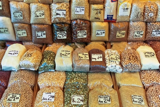 Bags full of different kinds of wheat, nuts and beans on a market stand