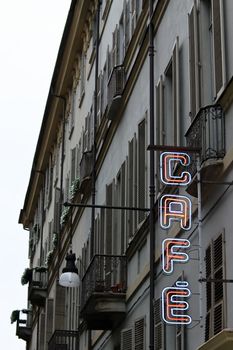 A neon sign for a caf� on an old italian facade