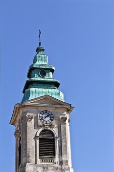 An old church tower with a clock in the center of Vienna